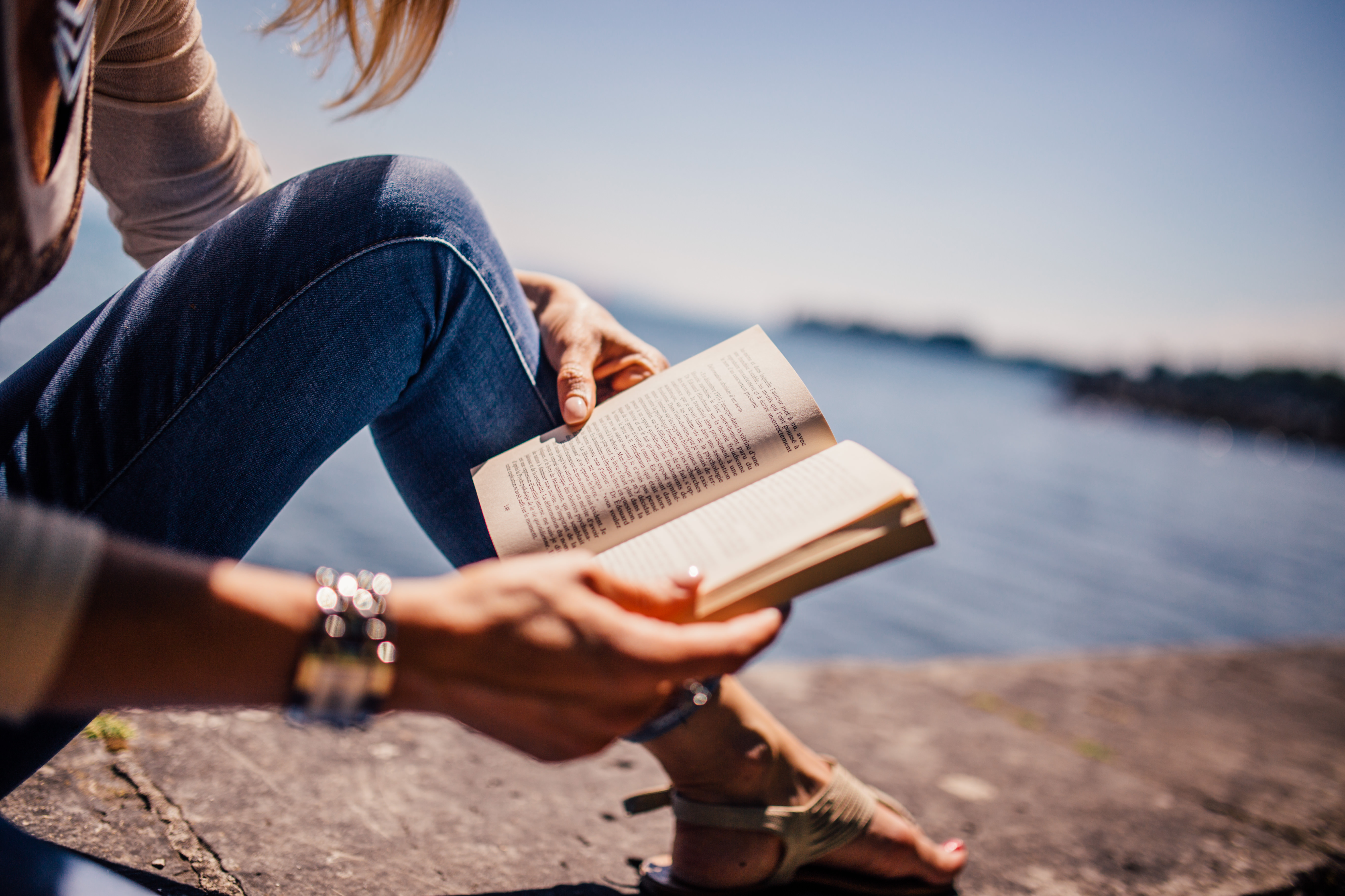 girl reading book on beach